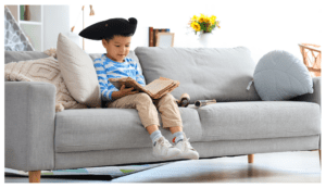 chlapec-číta-knihu-na-gauči